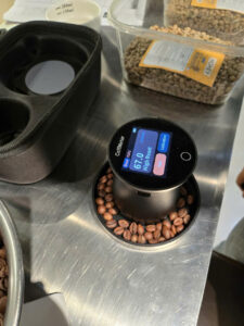 Máy đo màu rang cà phê CoffMeter hiển thị chỉ số 67.0 High Roast trên khay mẫu hạt rang tại Stone Village Lab