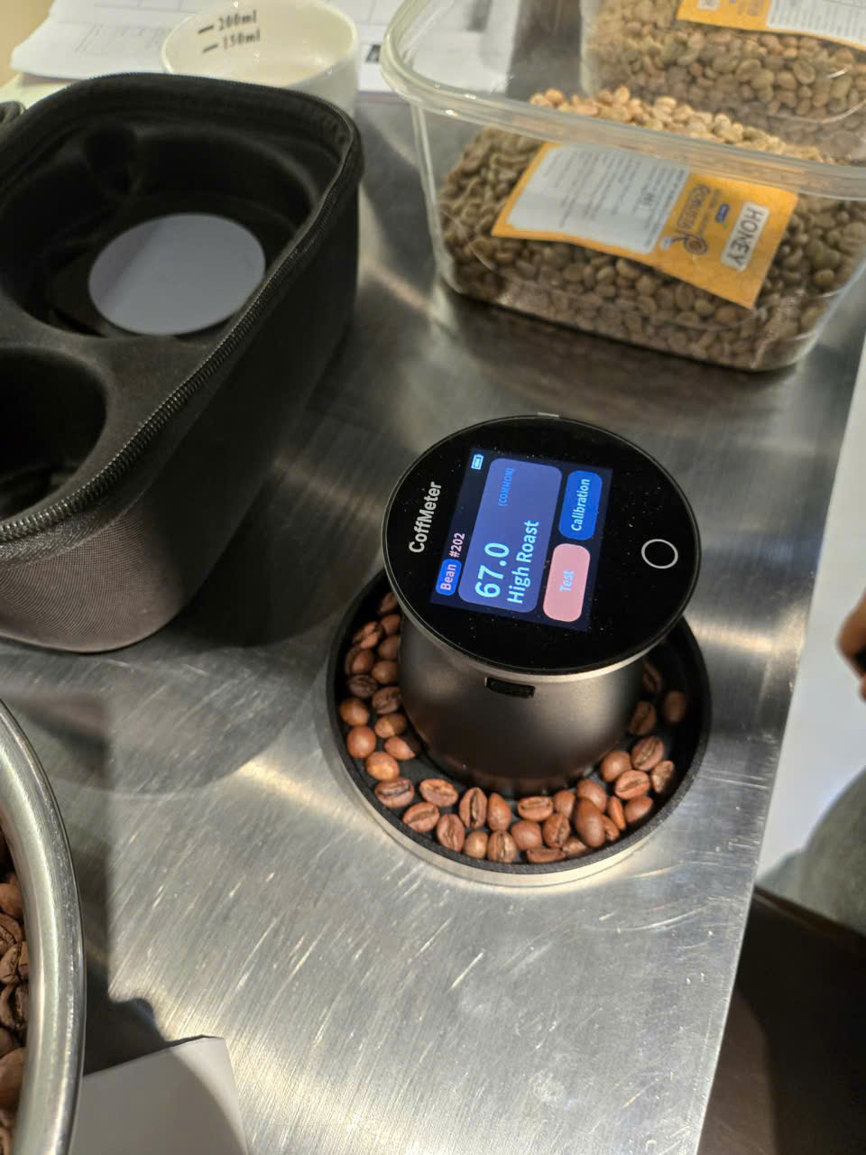 Đo màu rang cà phê bằng máy CoffMeter – kết quả 67.0 High Roast Máy đo màu rang cà phê CoffMeter hiển thị chỉ số 67.0 High Roast trên khay mẫu hạt rang tại Stone Village Lab