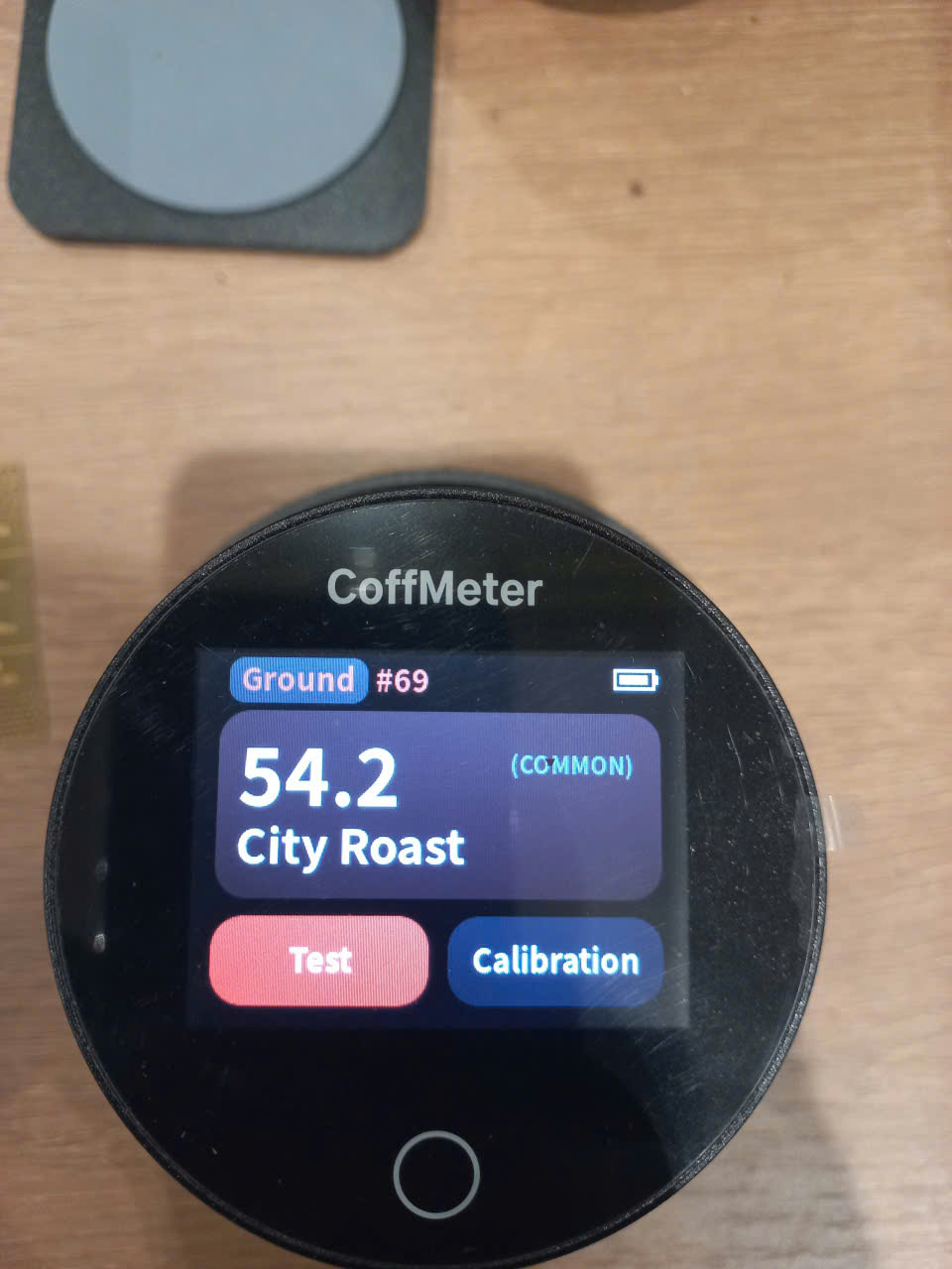 Máy đo màu CoffMeter hiển thị 54.2 City Roast khi đo mẫu bột cà phê rang trong dịch vụ setup profile rang từ xa