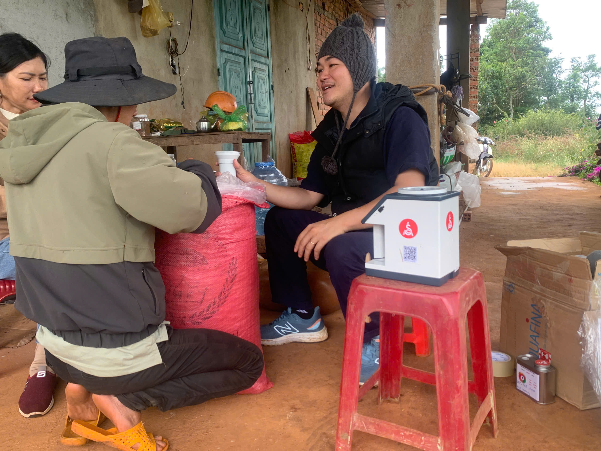 Chuyên gia Stone Village Lab trò chuyện cùng gia đình nông dân Đắk Song bên máy đo độ ẩm cà phê