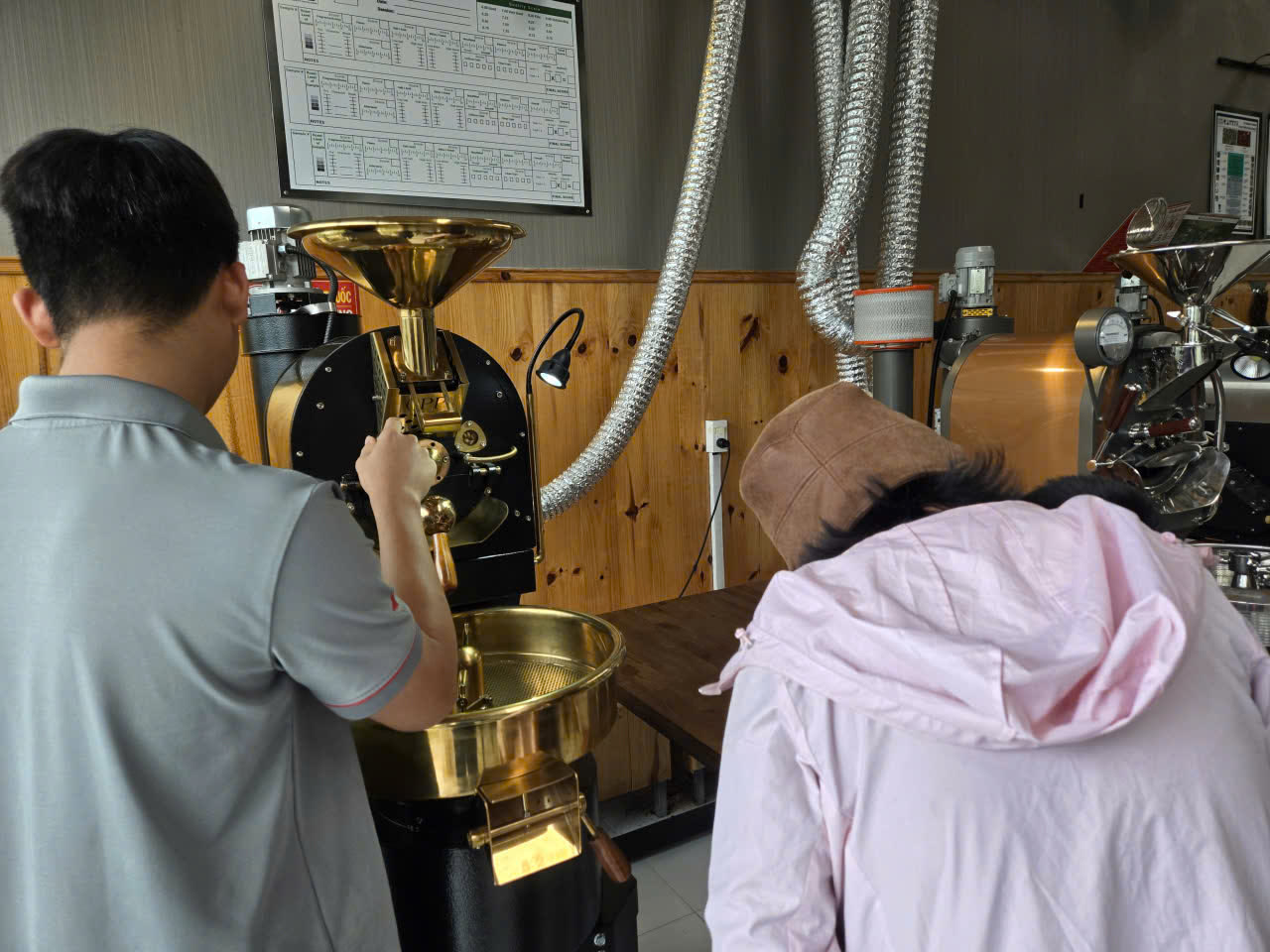 Giảng viên hướng dẫn theo mẻ rang trên máy rang trống đồng bên bảng theo dõi profile rang, các bé quan sát từng bước.