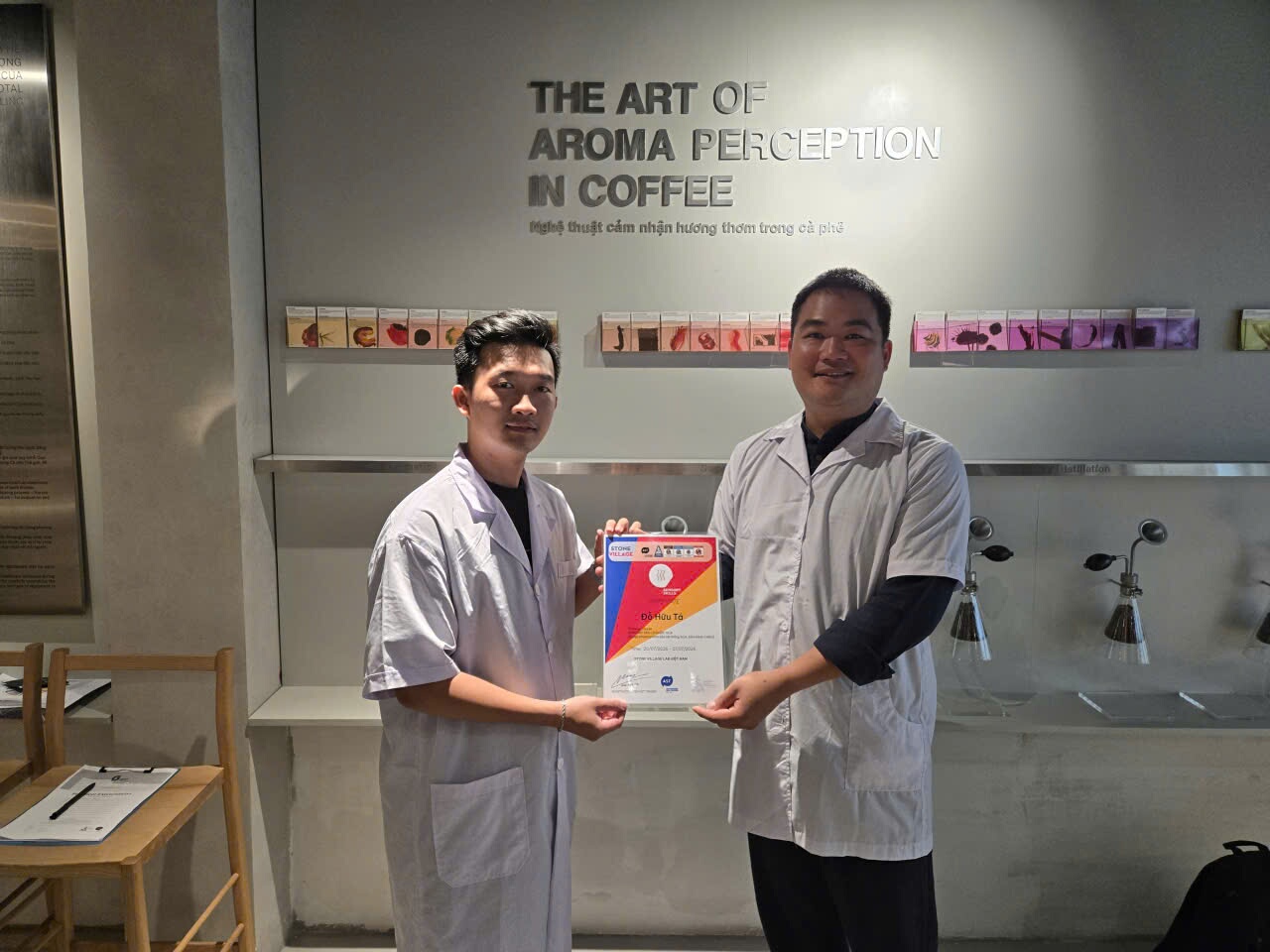Trao giấy chứng nhận trước tường The Art of Aroma Perception in Coffee tại Lab TP.HCM
