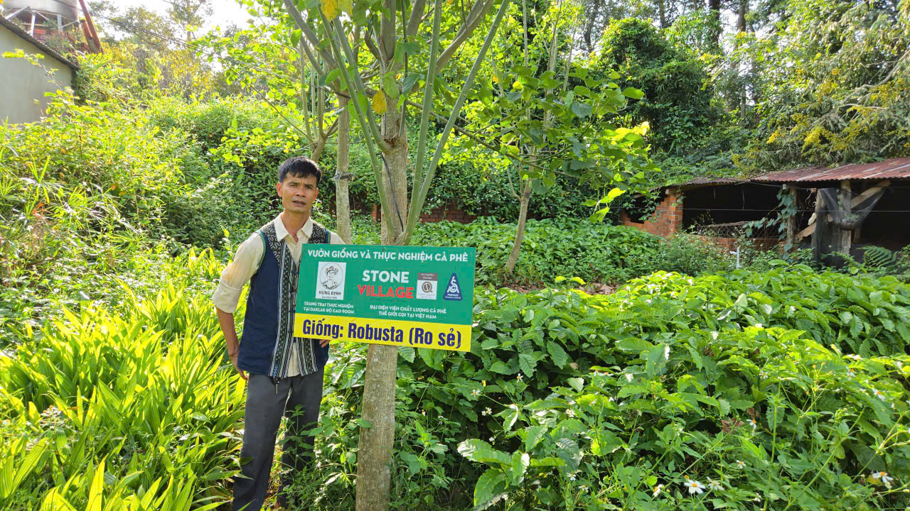 Chủ Hưng Định Farm trong trang phục thổ cẩm bên biển khu giống Arabica tại vườn thực nghiệm cà phê Stone Village Đắk Lắk