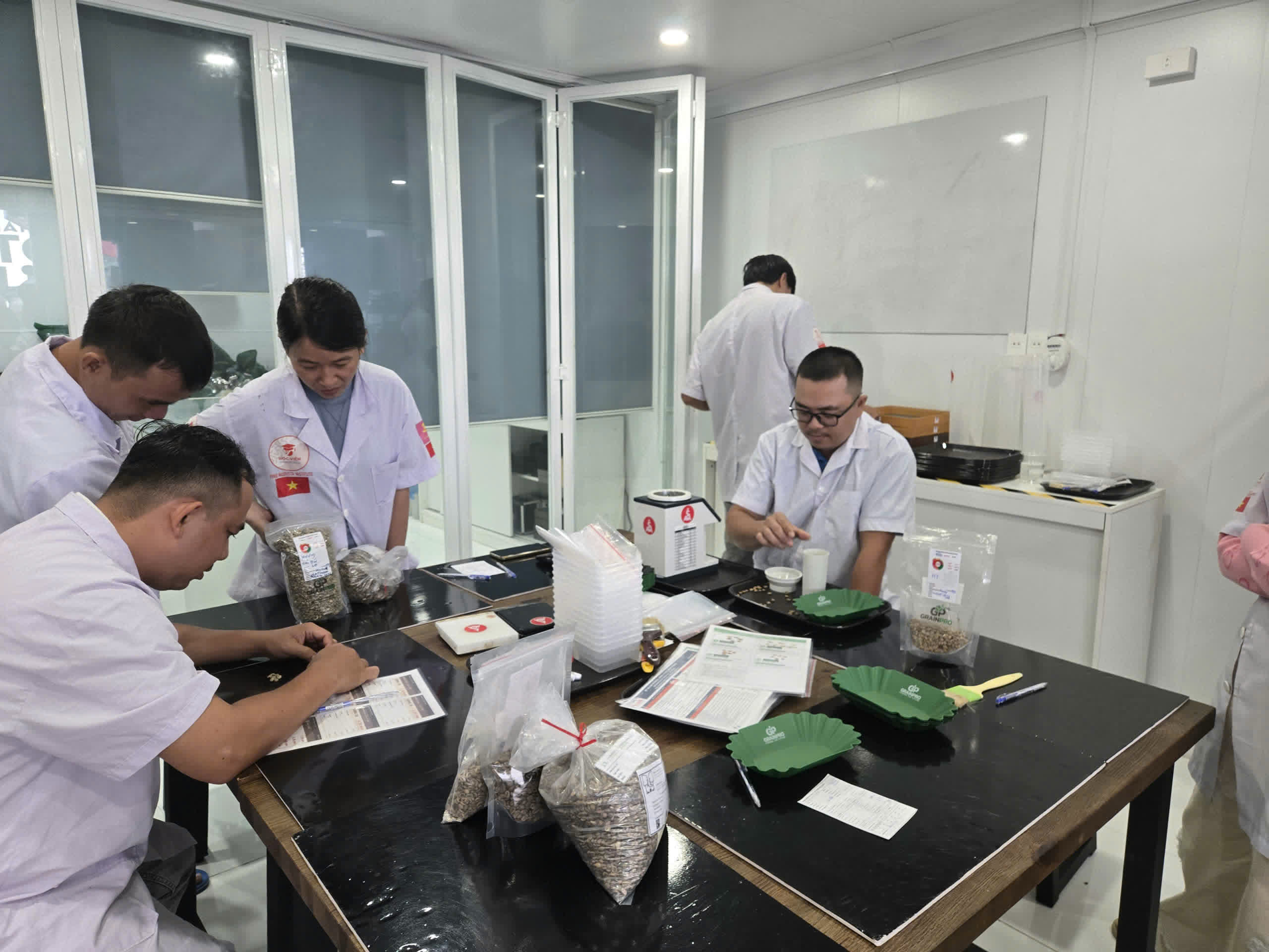 Bàn thực hành với cân điện tử và túi mẫu trong lớp SCA Green Bean