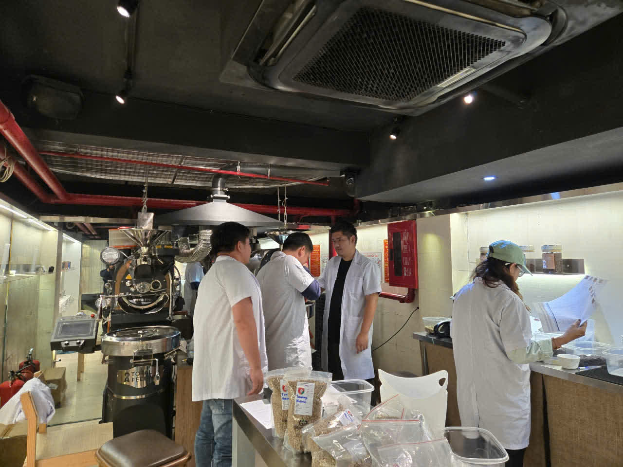 Học viên đứng quanh máy rang trong buổi thực hành của lớp SCA Roasting