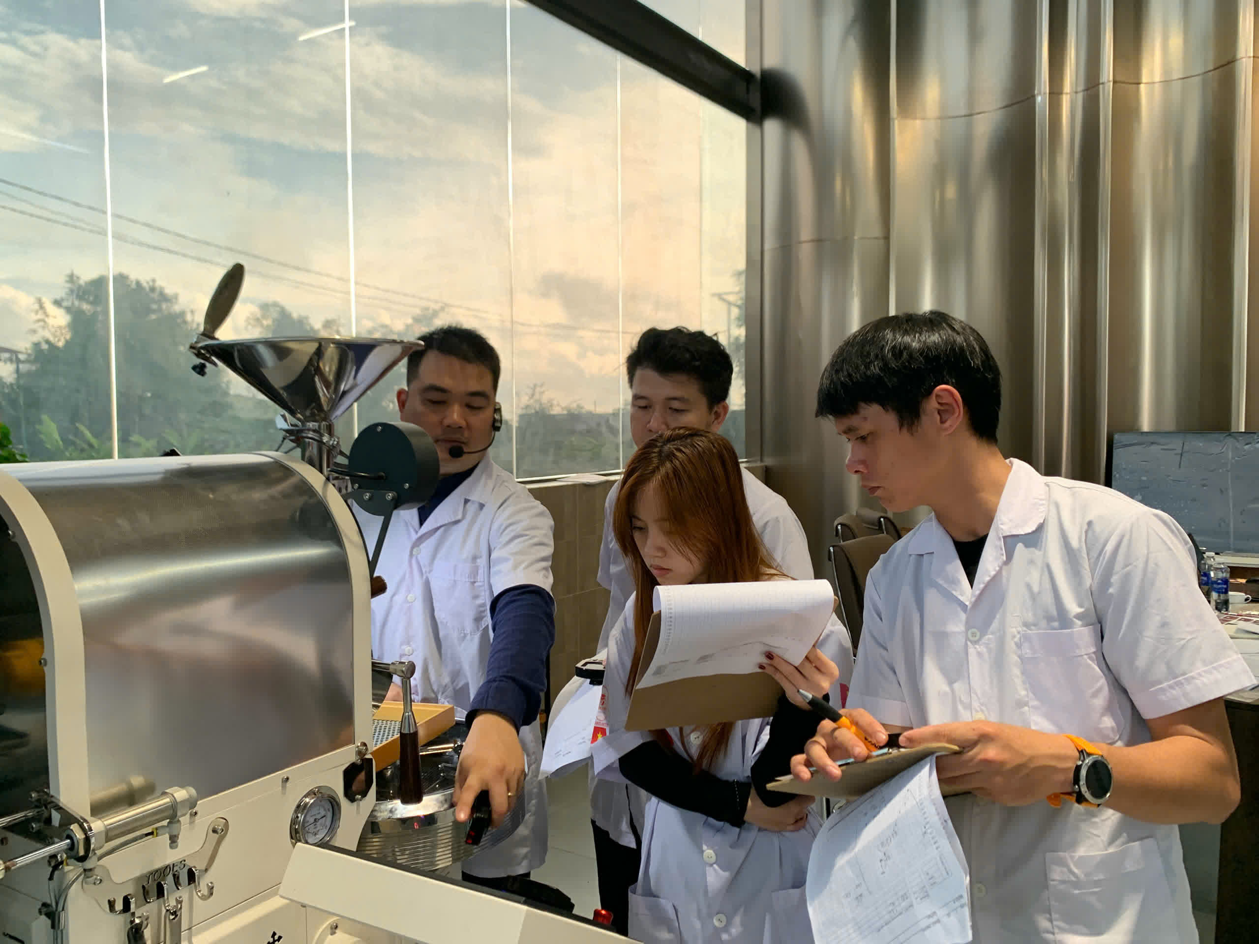 Nhóm học viên tập trung quanh máy rang cùng giảng viên