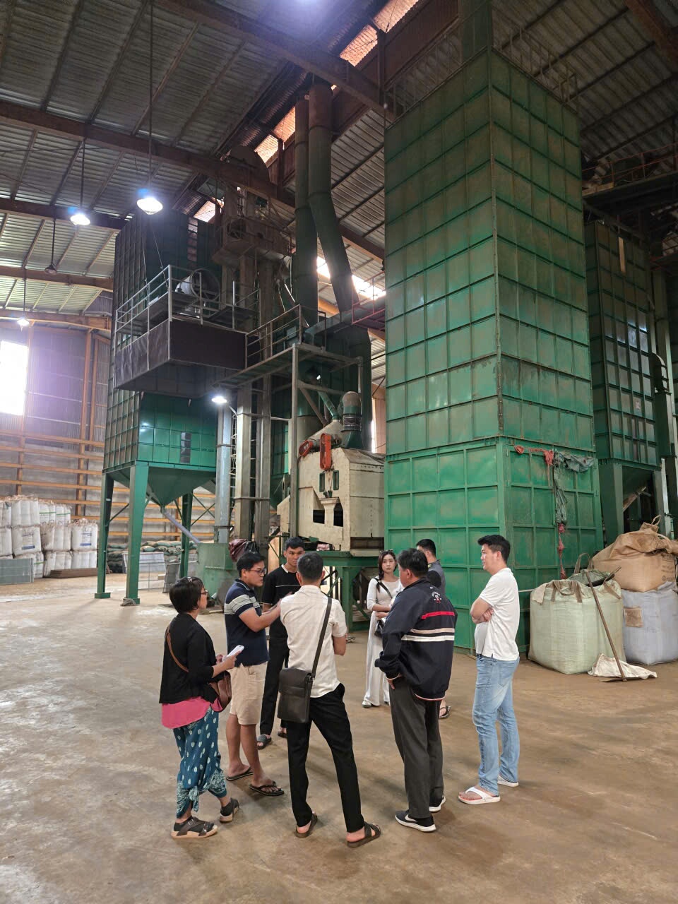 Nhóm người học quan sát khu vực máy phân loại và bao hàng trong nhà máy cà phê
