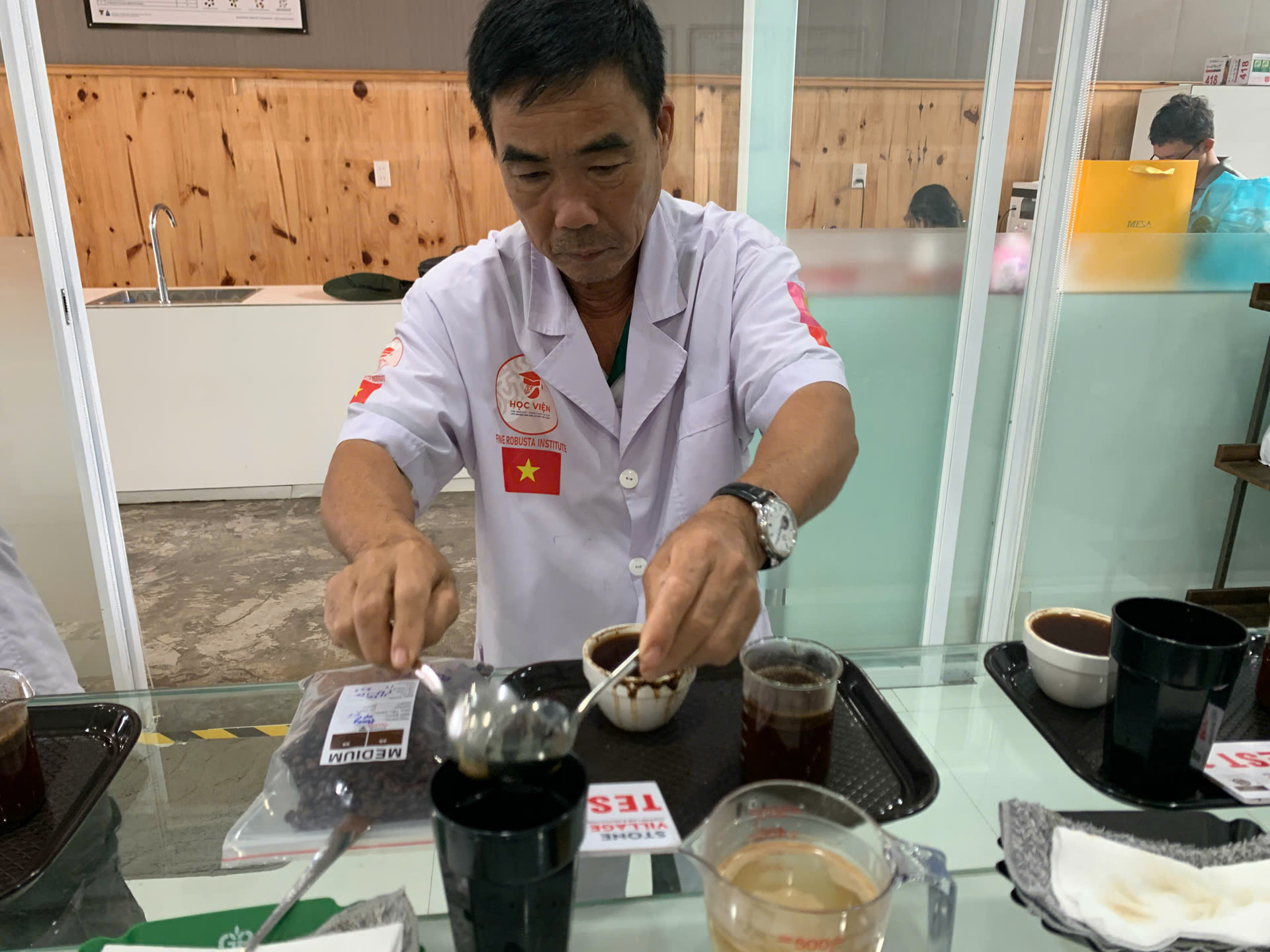 Bàn cupping đánh giá mẻ rang với cốc mẫu và thìa cupping