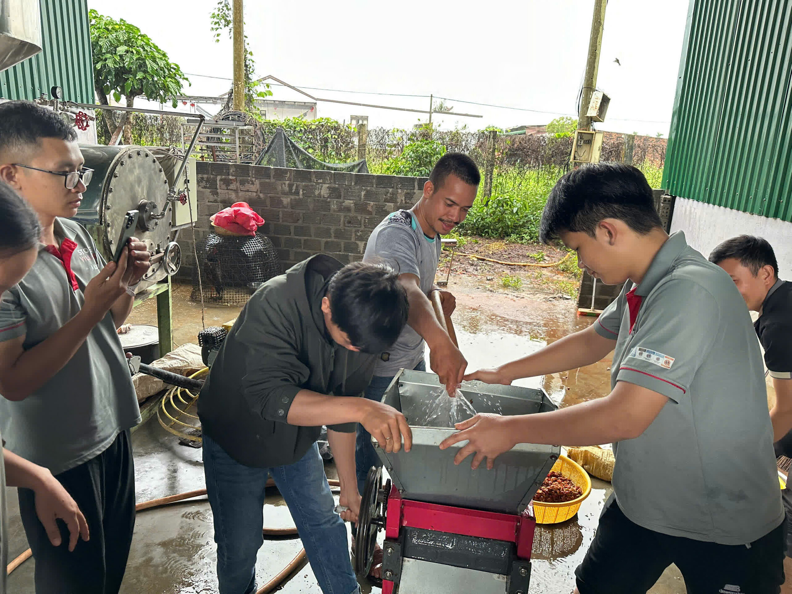 Học viên vận hành máy xát tươi cà phê ngoài sân nhà máy
