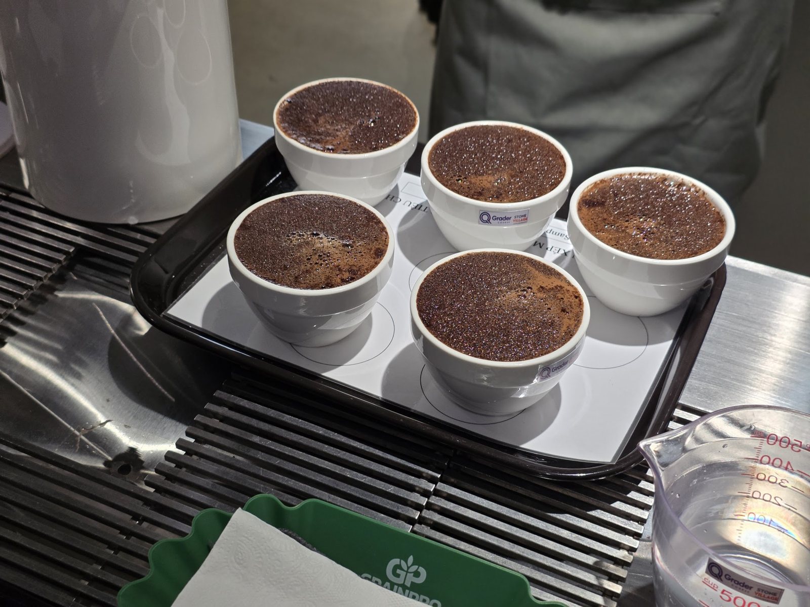 Năm chén cupping sau khi rót nước, lớp váng bột cà phê nổi trên mặt