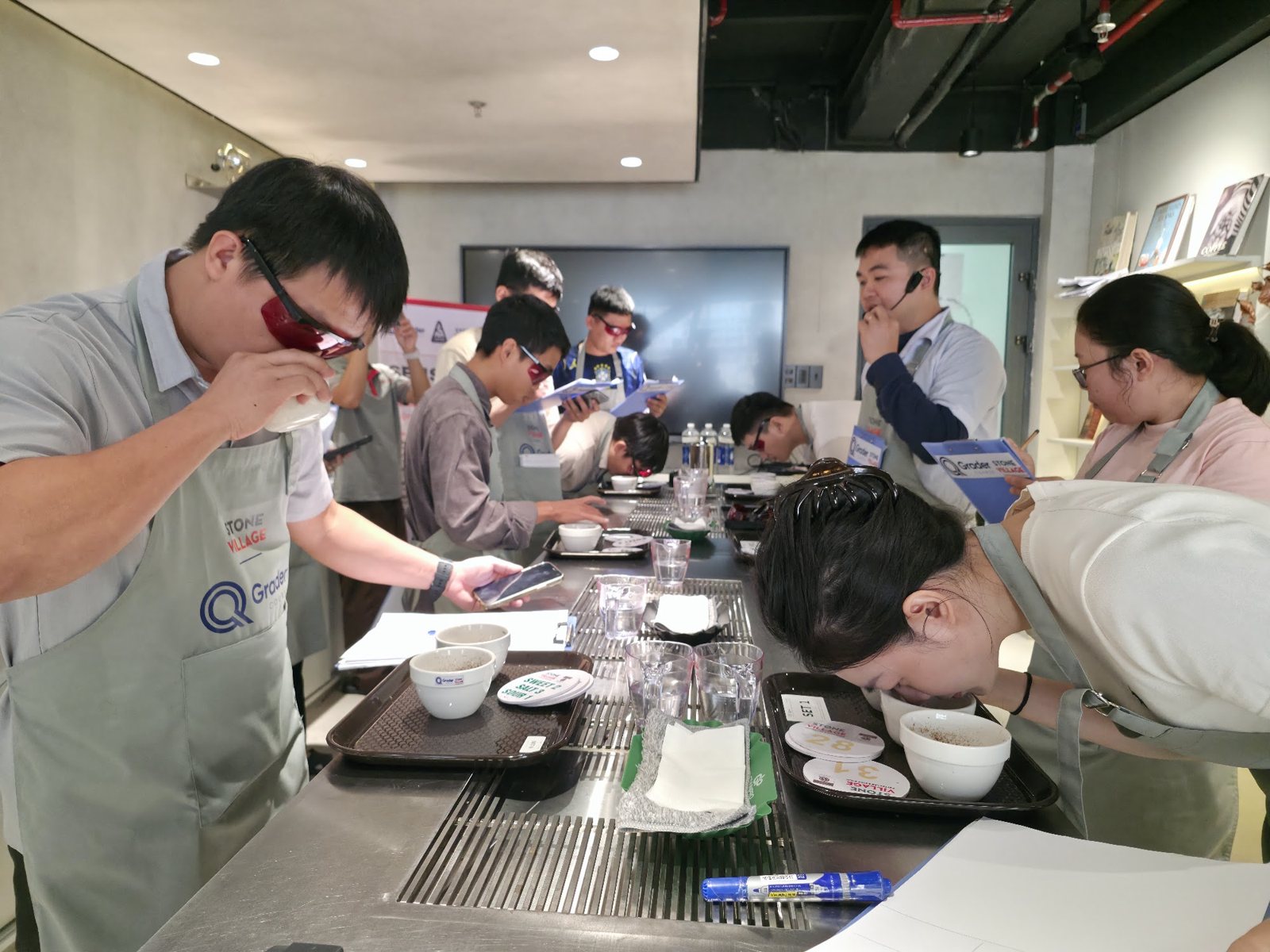 Học viên đeo kính đỏ ghi chép bên bàn thử nếm